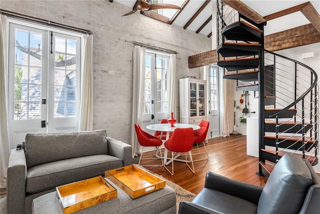 living room with french doors, brick wall, beam ceiling, and hardwood / wood-style floors