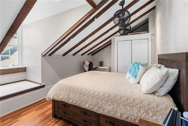 bedroom featuring a closet, lofted ceiling with beams, and light hardwood / wood-style flooring