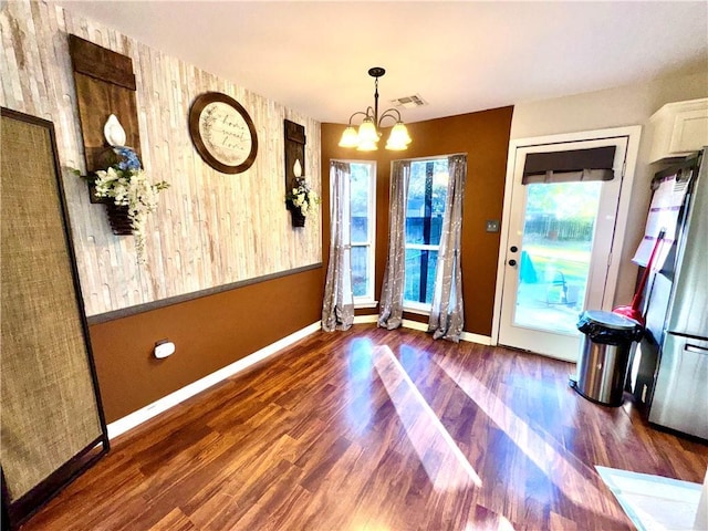 doorway with dark hardwood / wood-style floors, a wealth of natural light, and an inviting chandelier