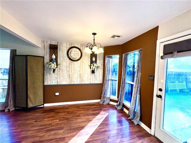 doorway with dark wood-type flooring and a notable chandelier