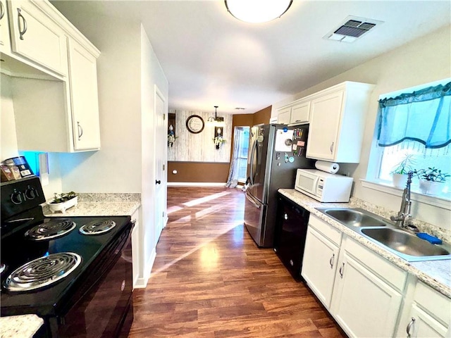 kitchen featuring dark wood-type flooring, sink, black appliances, a notable chandelier, and white cabinets