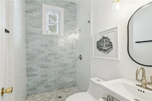 bathroom with tiled shower, toilet, and sink