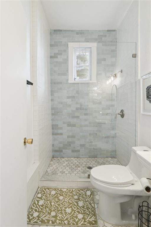 bathroom with tile patterned floors, tiled shower, and toilet