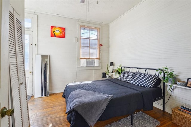 bedroom with hardwood / wood-style floors, cooling unit, and ornamental molding