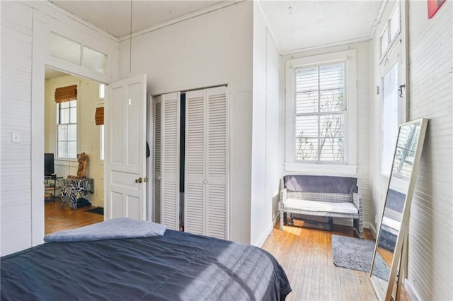 bedroom with hardwood / wood-style floors, crown molding, and a closet