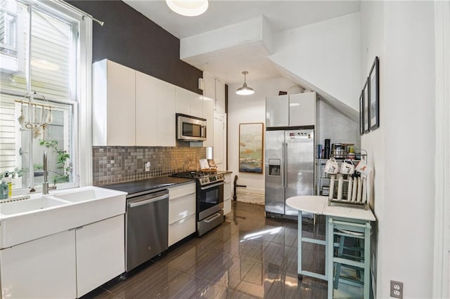 kitchen with appliances with stainless steel finishes, sink, decorative light fixtures, white cabinetry, and plenty of natural light