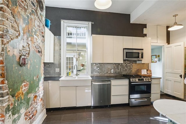 kitchen with decorative backsplash, appliances with stainless steel finishes, white cabinetry, and pendant lighting