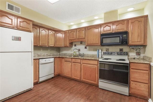 kitchen with sink, tasteful backsplash, light stone counters, dark hardwood / wood-style flooring, and white appliances