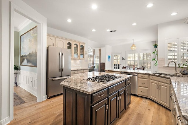 kitchen with cream cabinets, sink, light hardwood / wood-style flooring, dark brown cabinetry, and stainless steel appliances