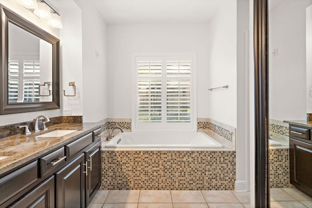 bathroom with tile patterned floors, vanity, and a relaxing tiled tub