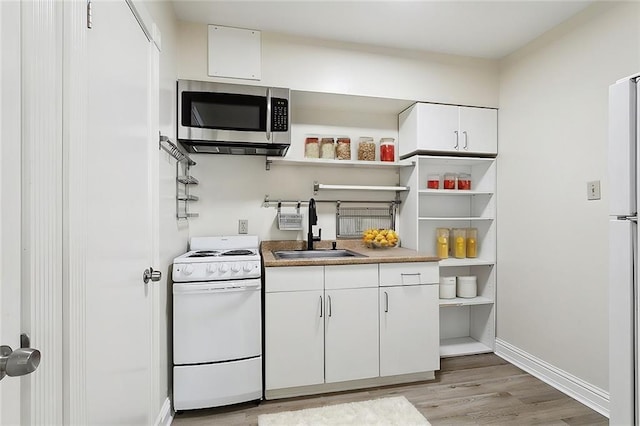 kitchen featuring white appliances, white cabinets, light wood-type flooring, and sink