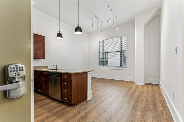 kitchen featuring decorative light fixtures, stainless steel dishwasher, light hardwood / wood-style floors, and sink