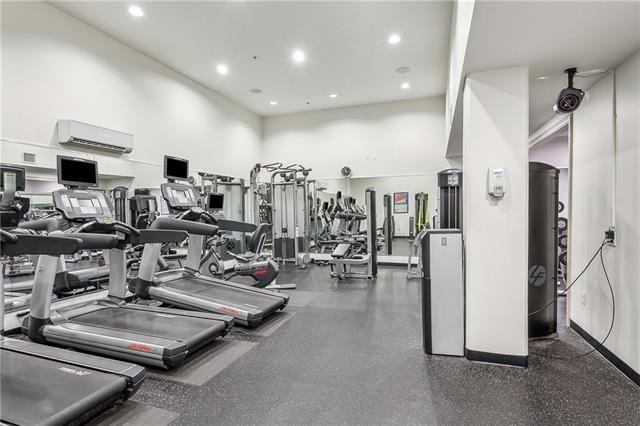 gym featuring a wall unit AC and a towering ceiling