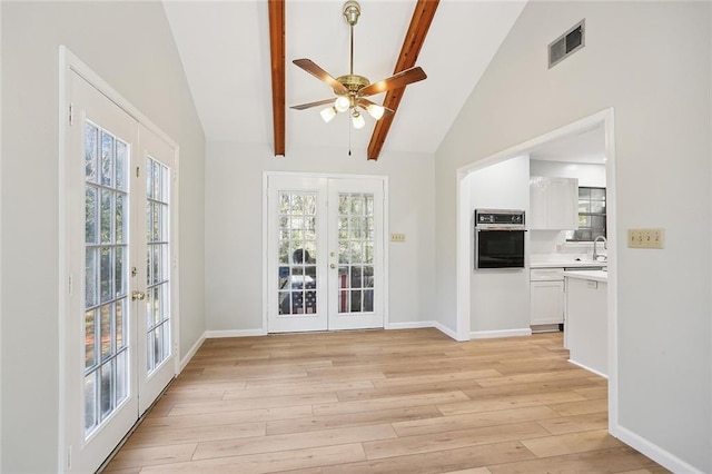 unfurnished living room with french doors, vaulted ceiling with beams, ceiling fan, and a healthy amount of sunlight