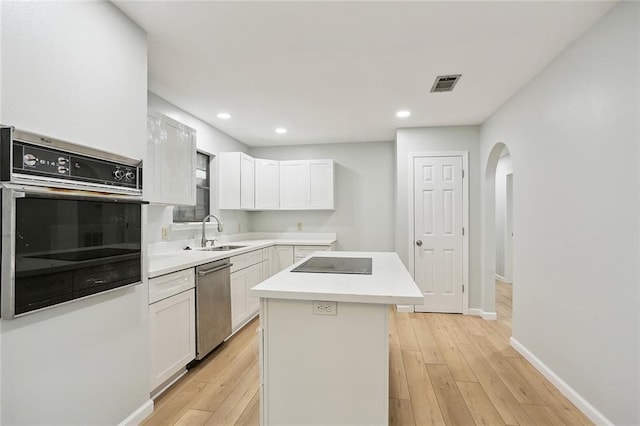 kitchen featuring white cabinetry, sink, stainless steel dishwasher, oven, and a kitchen island