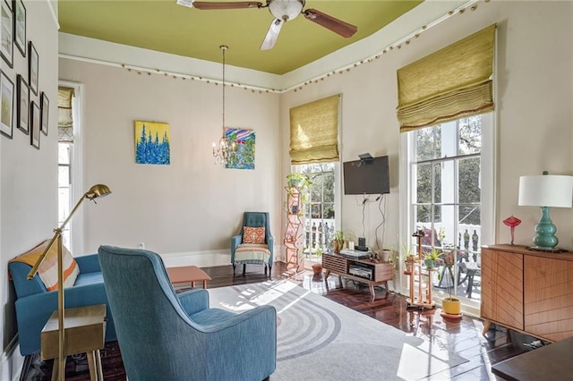 living area with ceiling fan with notable chandelier and a healthy amount of sunlight