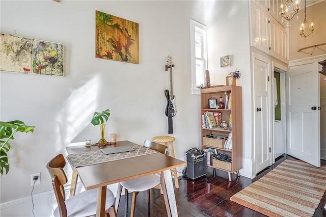 dining area with dark wood-type flooring and a notable chandelier