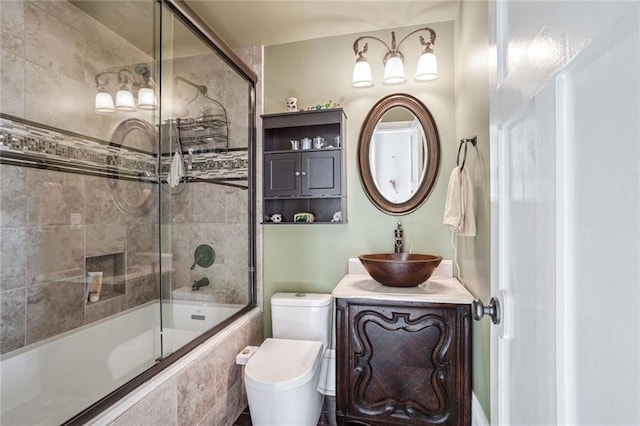 full bathroom featuring vanity, toilet, and shower / bath combination with glass door