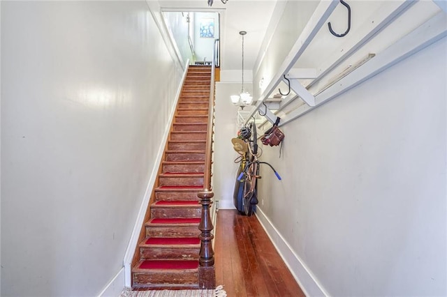 stairway featuring hardwood / wood-style flooring and a notable chandelier