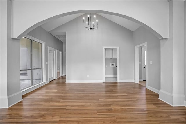 unfurnished living room with a notable chandelier, wood-type flooring, and high vaulted ceiling