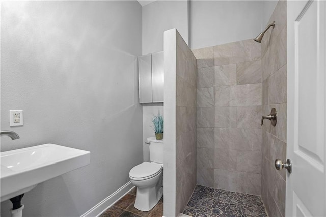 bathroom featuring tiled shower, sink, and toilet