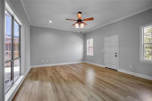 spare room featuring a wealth of natural light, ornamental molding, and light wood-type flooring