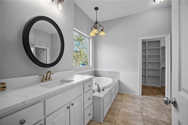 bathroom featuring a tub, tile patterned flooring, a notable chandelier, vaulted ceiling, and vanity