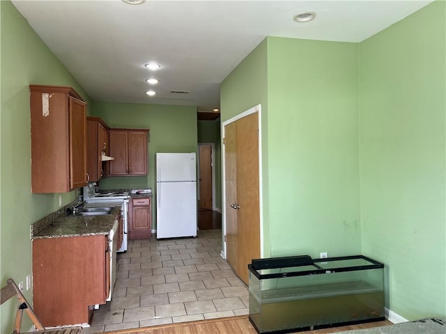 kitchen featuring light tile patterned flooring, sink, dark stone countertops, white refrigerator, and gas range