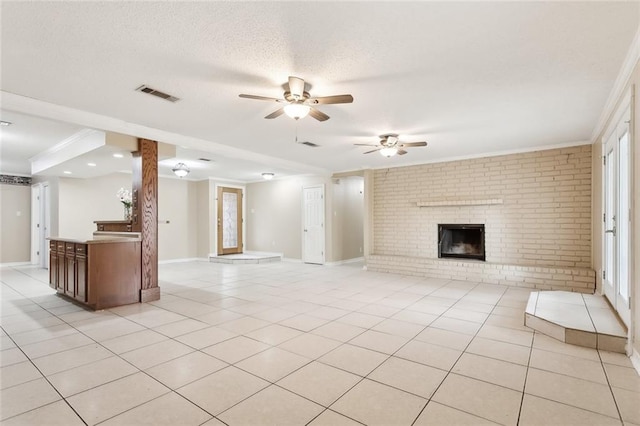 unfurnished living room with ceiling fan, light tile patterned flooring, a textured ceiling, and a brick fireplace