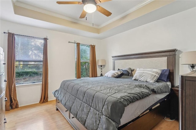 bedroom featuring a tray ceiling, multiple windows, and ceiling fan