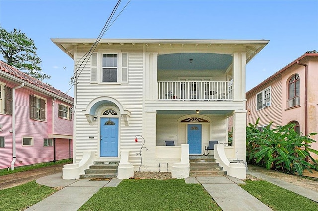 view of front facade with a balcony and a front lawn