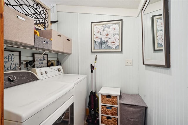 clothes washing area with washing machine and clothes dryer and wooden walls