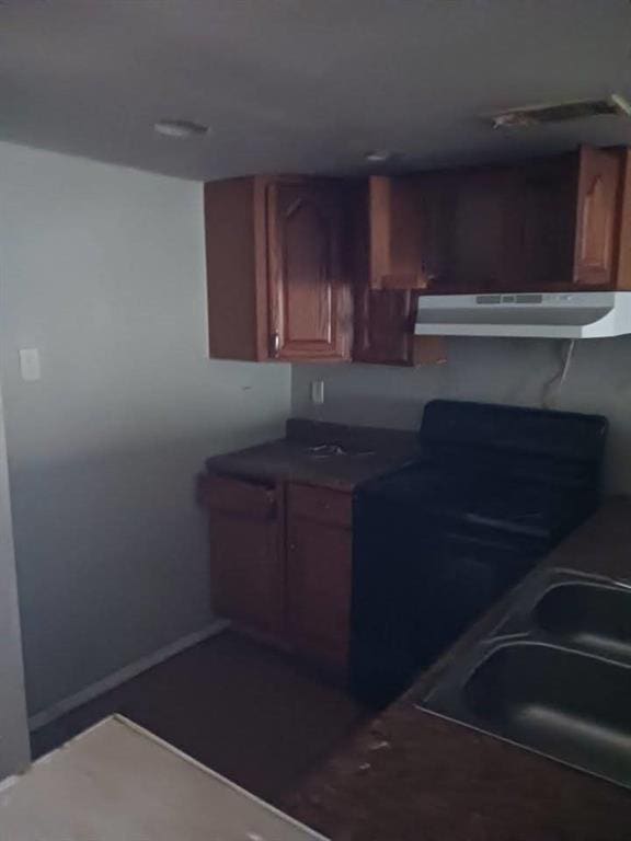 7112 Barrington Ct, New Orleans, LA 70128 - kitchen with under cabinet range hood, dark countertops, and brown cabinetry