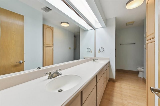 bathroom with hardwood / wood-style flooring, vanity, and toilet