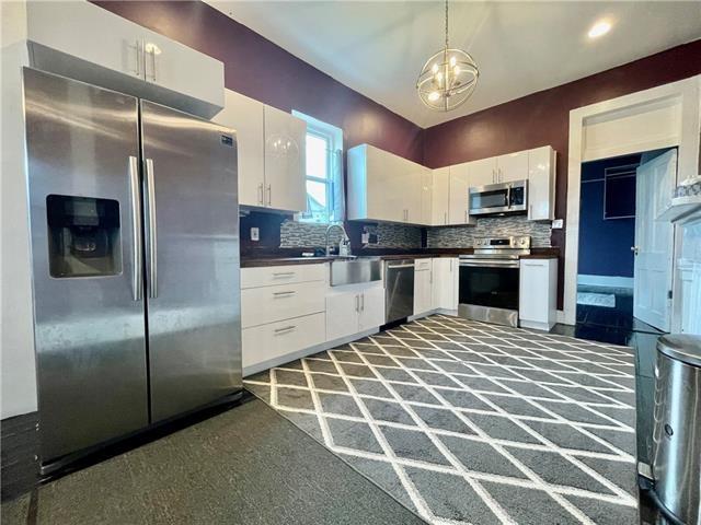 kitchen with decorative light fixtures, stainless steel appliances, and white cabinetry