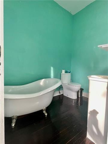 bathroom with a bath, hardwood / wood-style flooring, and toilet