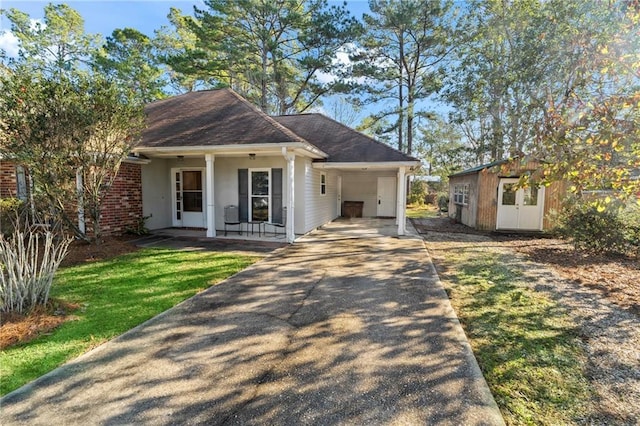 ranch-style home featuring a front lawn, covered porch, and a carport