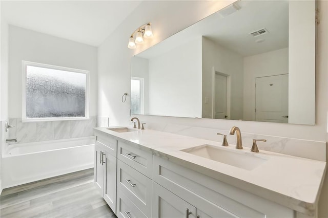 bathroom with a bath, hardwood / wood-style flooring, and vanity