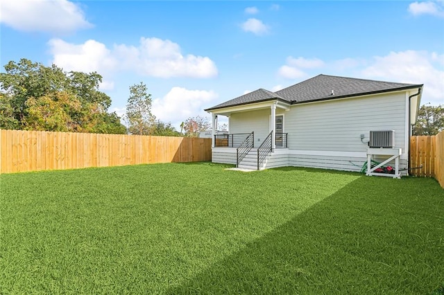 rear view of property featuring a lawn and central AC unit