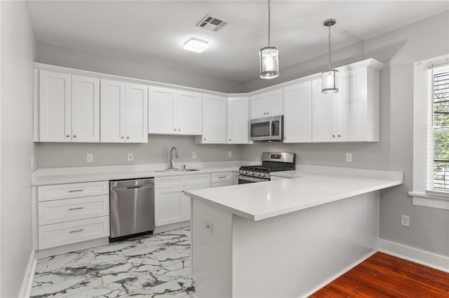 kitchen with sink, stainless steel appliances, kitchen peninsula, pendant lighting, and white cabinets