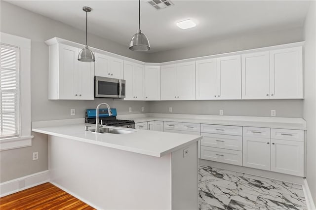 kitchen featuring kitchen peninsula, white cabinetry, hanging light fixtures, and stainless steel appliances