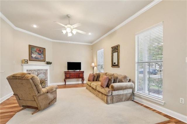 living room featuring wood-type flooring, a brick fireplace, ornamental molding, and ceiling fan