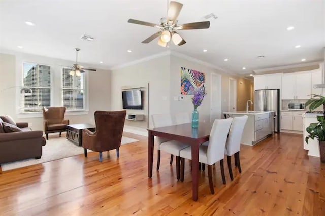 dining room featuring ornamental molding, light wood-type flooring, ceiling fan, and sink