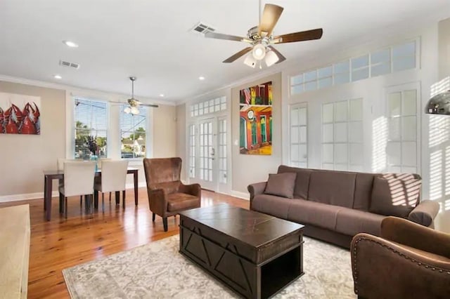 living room featuring ornamental molding, ceiling fan, and light wood-type flooring