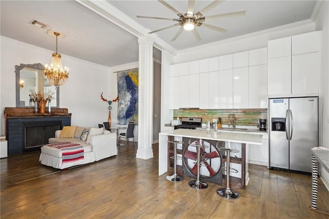 kitchen featuring ornate columns, stainless steel appliances, ornamental molding, pendant lighting, and white cabinetry