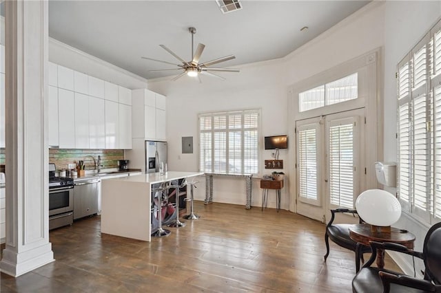 kitchen featuring a center island, stainless steel appliances, crown molding, white cabinets, and ceiling fan