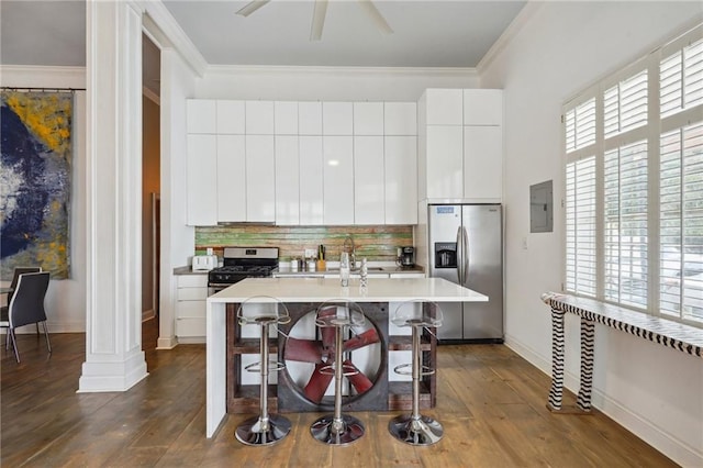 kitchen with a breakfast bar area, appliances with stainless steel finishes, a kitchen island with sink, ornamental molding, and white cabinets