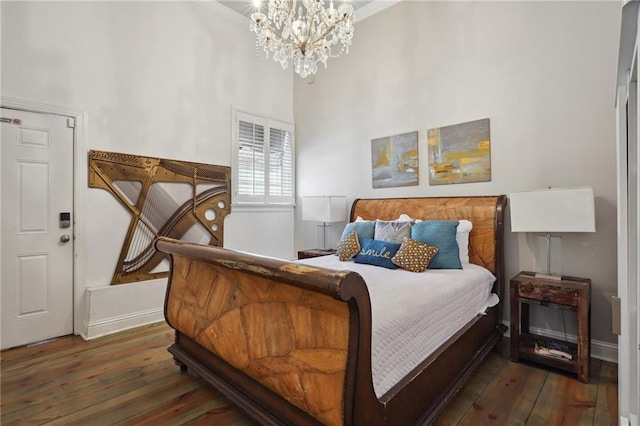 bedroom featuring an inviting chandelier, crown molding, dark wood-type flooring, and a high ceiling