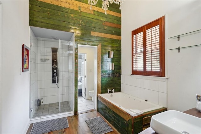 full bathroom with wood walls, wood-type flooring, sink, separate shower and tub, and toilet