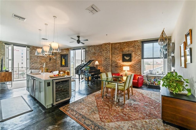 kitchen featuring decorative light fixtures, an island with sink, wine cooler, and a wealth of natural light